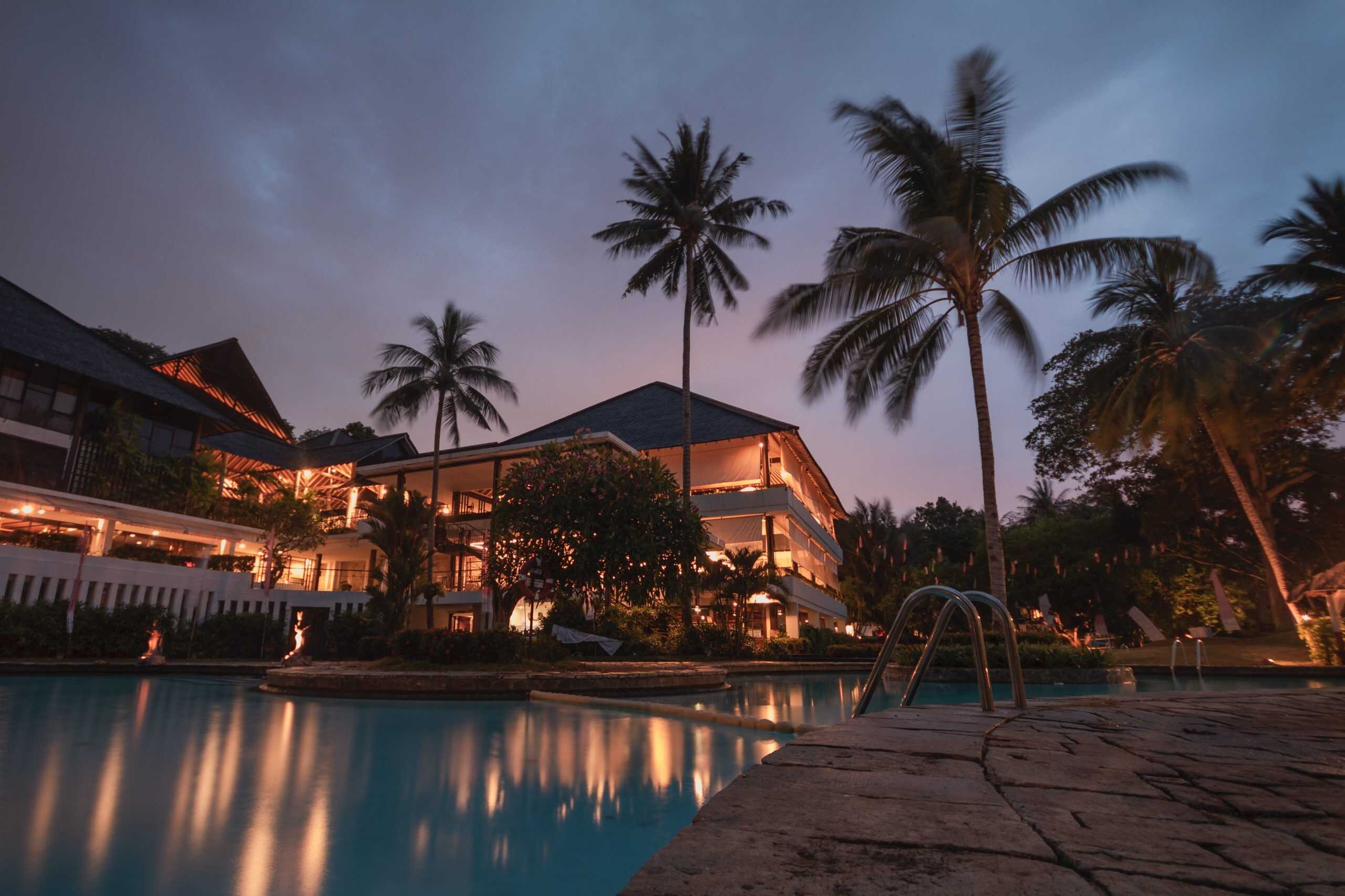 building with a pool andpalms