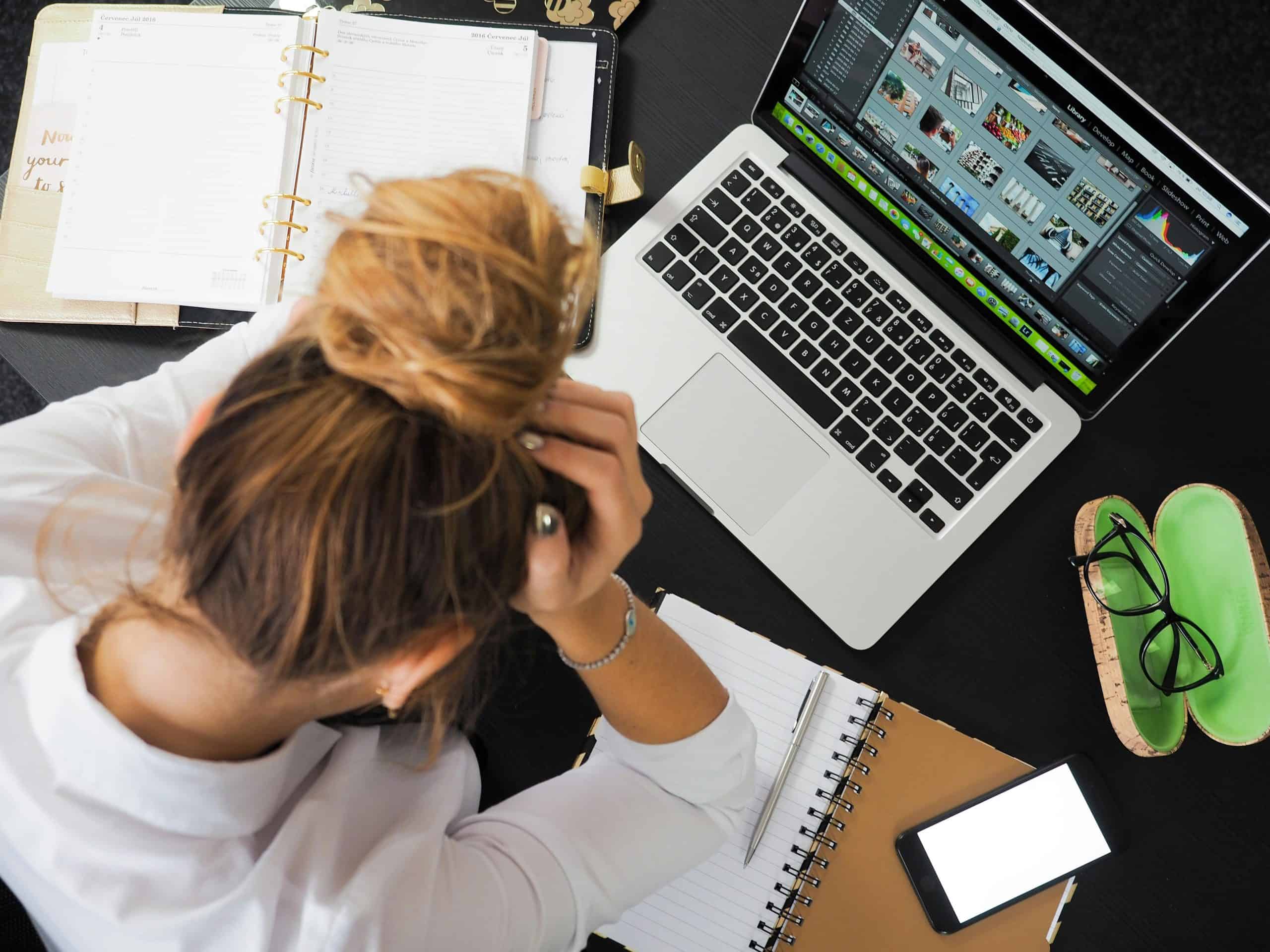 woman by laptop holding her head